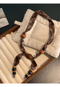 Detail view of ethnic floral fabric necklace with wooden beads and sunflower patterns