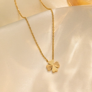 Elegant 18k gold-plated four-leaf clover necklace on luxury beige silk fabric background