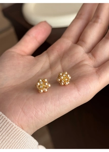 Close-up of elegant flower cluster pearl earrings with crystals held in a hand