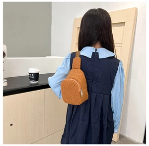 Rear view of brown plush crossbody bag on child's back showing size and fuzzy texture