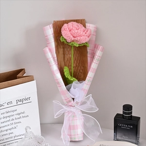 Detailed close-up of a single hand-knitted pink rose bouquet in festive gift wrapping