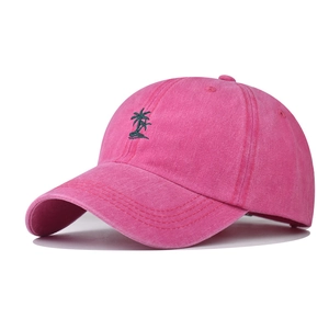 Detail of embroidered green palm tree on washed pink cotton baseball cap fabric