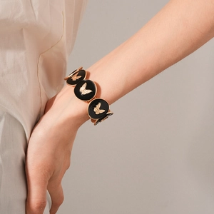 Detail of vintage gold bracelet with black enamel circles and butterfly motifs on wrist