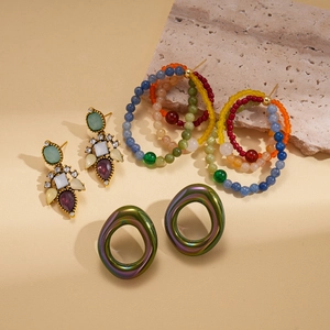 Artistic arrangement of vintage beaded and rhinestone drop earrings on stone background