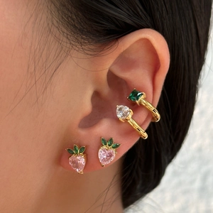 Detail of stacked ear set featuring pink heart studs and square green zircon cuff