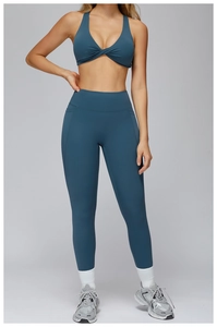 Detail view of teal blue high waist yoga leggings and criss-cross knot sports bra