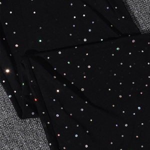 Detail of sheer black mesh fabric featuring shimmering colorful rhinestones for evening wear
