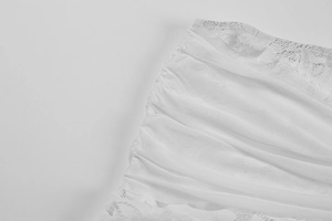 Detailed macro view of white lace stitching and pleated mesh fabric on long sexy dress