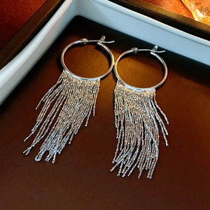 Detailed view of silver metallic tassel drop earrings on a jewelry tray stand
