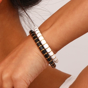 Detail of enamel stretch bracelets in black and white with 18K gold-plated metal segments