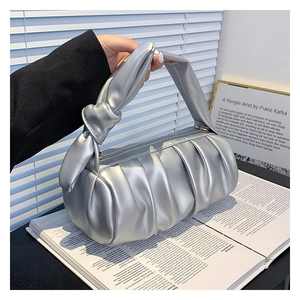 Detail of silver pleated cloud bag with knotted handle in a stylish lifestyle setting