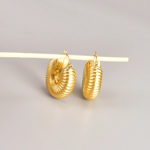 Golden chunky hoop earrings with twisted spiral texture hanging on a wooden stand