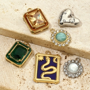 Vintage style geometric pendants with colorful emerald and amber stones on beige sandstone
