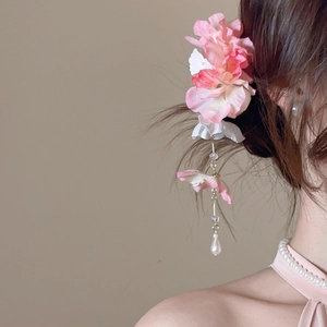 Détail de la pince à cheveux fleur en soie rose avec pompon doré et perle pendante