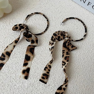 Detailed macro view of stylish leopard print chiffon ribbon on large golden metal hoop earrings