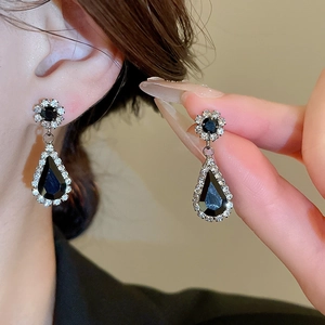 Detailed view of silver flower earrings with black teardrop stones and tiny rhinestones