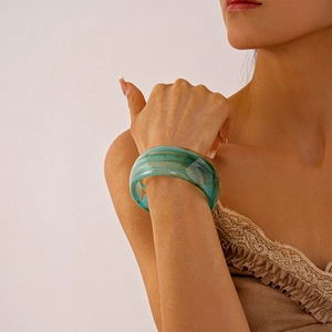 Close-up of marbled acrylic bangle with green and blue patterns on model's wrist