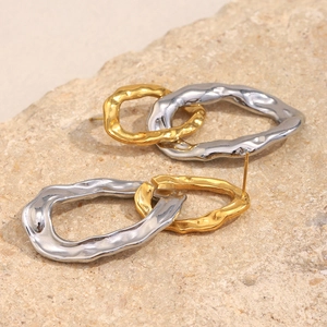 Macro detail of interlocking gold and silver hammered textured stud earrings on stone