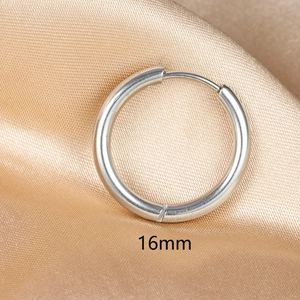 Detailed macro view of 16mm polished silver stainless steel hoop earring on silk fabric