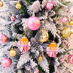 Sapin de Noël décoré avec des boules roses et dorées, lunes et figurines d'anges