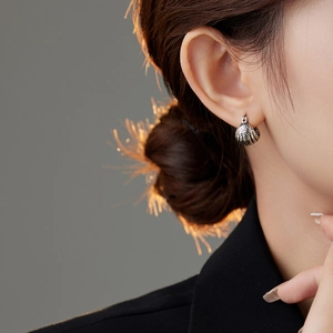 Close-up of vintage silver hoop earrings with lava texture on a model's ear