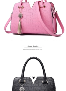 Detail of crocodile embossed handbag with V-shaped metal hardware and pendant charm