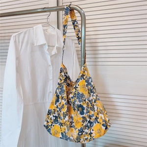 Detailed view of yellow and blue floral cotton hobo tote bag hanging on a rack