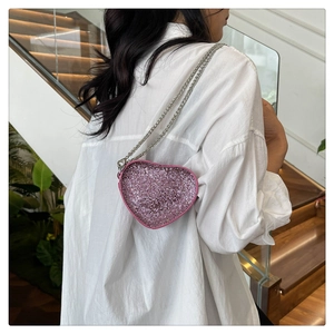Close-up of pink heart-shaped rhinestone handbag with silver metal chain on a model