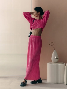 Detailed texture of pleated vibrant pink fabric on long sleeve top and maxi skirt set