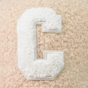 Beige faux shearling baseball cap featuring a white fleece embroidered C letter patch