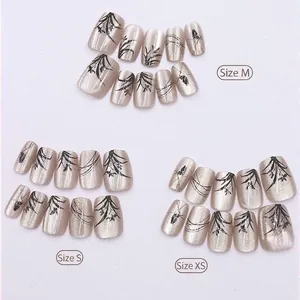 Cat eye champagne press-on nails with black bamboo patterns in sizes XS, S, and M