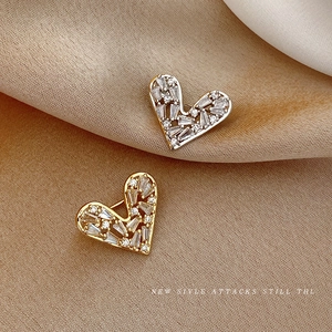 Elegant gold and silver heart brooches with sparkling zircons on beige silk fabric
