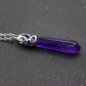 Macro detail of natural purple amethyst hexagonal crystal pendant with hollow silver clasp