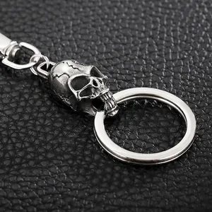 Creative stainless steel skull keychain with metal ring on black leather background