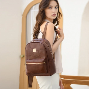 Detailed side view of a brown leather backpack with gold zippers shown on a model