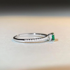 Macro side view of S925 silver emerald ring with pavé diamonds and step-cut green stone