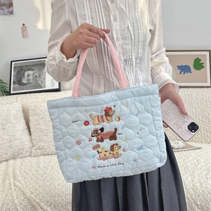 Detail of light blue quilted tote with cute dog embroidery and pink handles