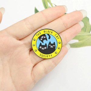 Badge rond en métal avec le motif The Black Cat Society présenté dans une main