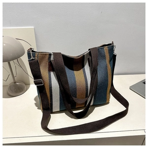 Close-up of a striped canvas tote bag with brown straps and metal adjustment buckles
