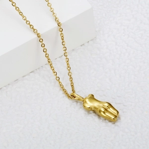 Artistic gold female torso pendant necklace on minimalist white geometric pedestal