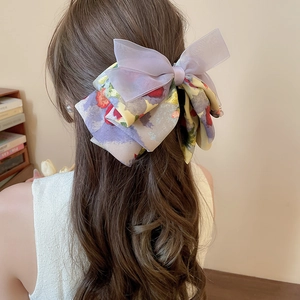Detail of a layered organza and floral bow hair claw clip styled on wavy hair
