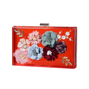 Transparent red acrylic evening clutch bag with colorful fabric flowers and gold leaf accents