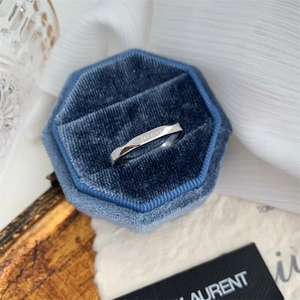 Close-up of twisted silver ring with Je t'aime engraving in a blue velvet box