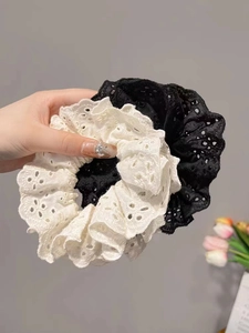 Detail of white lace scrunchie featuring delicate hollow embroidery and ruffled edges