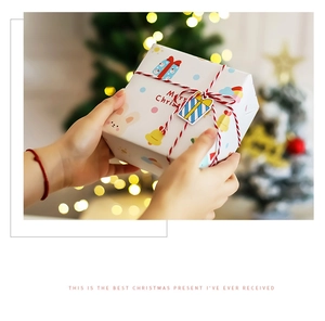 Close-up of hand holding a festive Merry Christmas gift box with bright bokeh lights