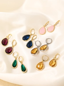 Selection of teardrop colorful gemstone earrings on beige silk fabric background