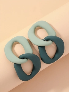 Close-up of interlocking geometric matte acrylic earrings in light and dark green