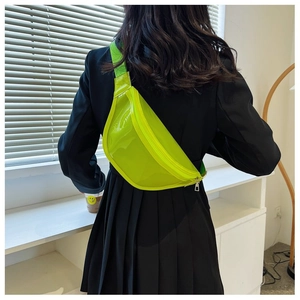 Detail of neon green transparent PVC chest bag worn over a black blazer for street style