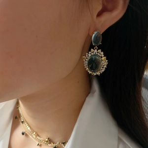 Detail of luxury mint blue cat-eye stone earrings with zircon halo on model