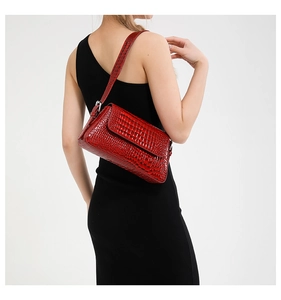 Detail of red crocodile pattern shoulder bag worn by model in black dress